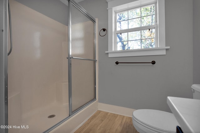 bathroom with wood-type flooring, toilet, and a shower with shower door