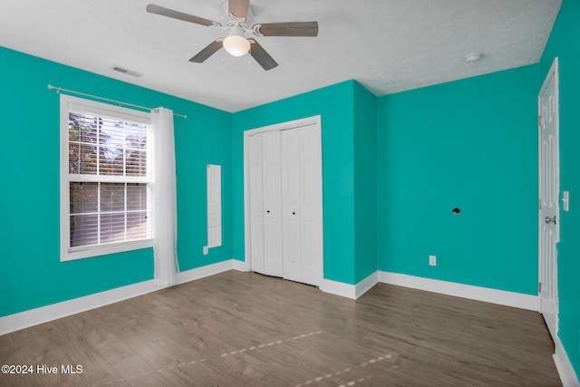 unfurnished bedroom featuring a closet, a textured ceiling, ceiling fan, and wood-type flooring