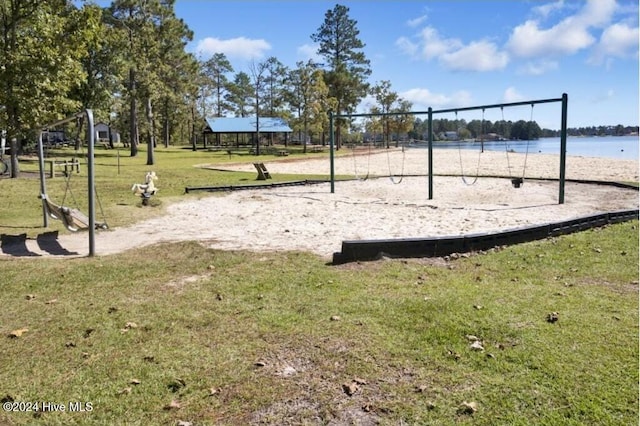 surrounding community with a playground, a yard, and a water view