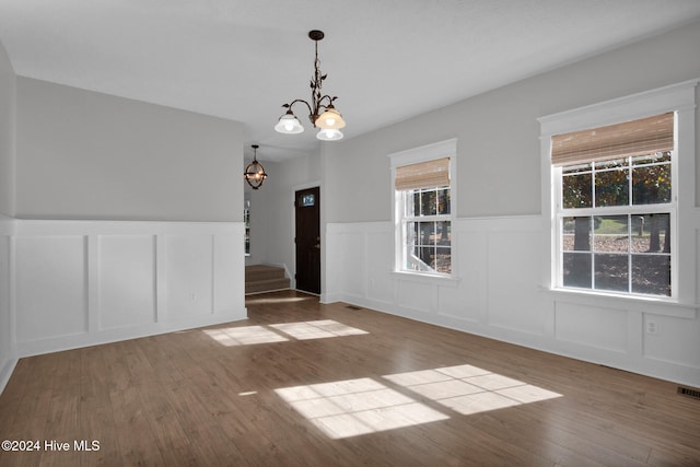 spare room featuring hardwood / wood-style floors, a wealth of natural light, and a chandelier