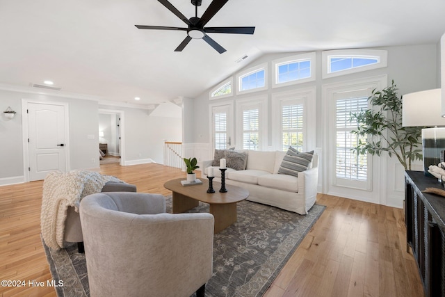 living room featuring light wood finished floors, visible vents, vaulted ceiling, and a ceiling fan