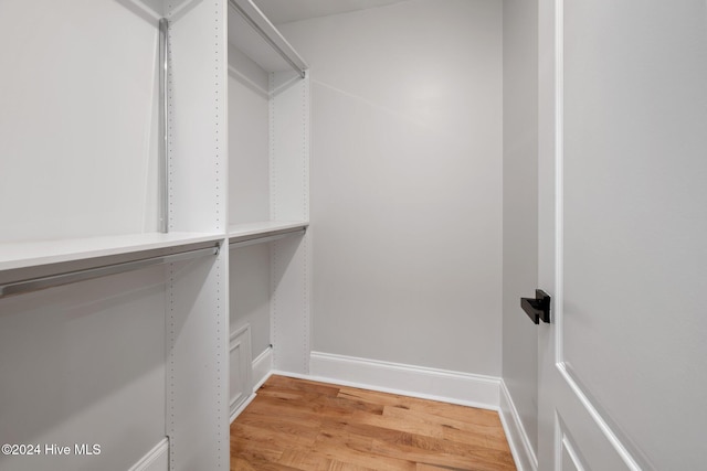 walk in closet with light wood finished floors