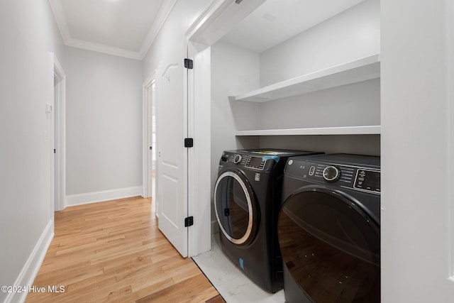 clothes washing area with washing machine and clothes dryer, ornamental molding, wood finished floors, laundry area, and baseboards