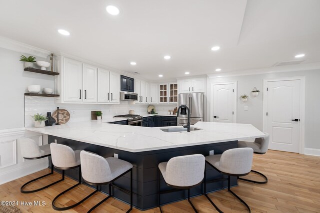 kitchen with sink, hanging light fixtures, kitchen peninsula, white cabinets, and appliances with stainless steel finishes