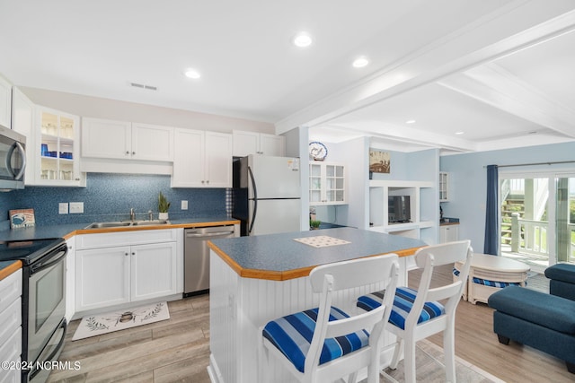 kitchen with stainless steel appliances, sink, light hardwood / wood-style flooring, and white cabinets