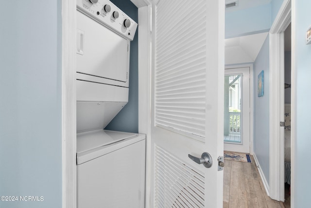 clothes washing area featuring light hardwood / wood-style flooring and stacked washer / dryer