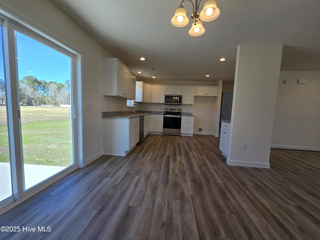 kitchen with dark hardwood / wood-style floors, sink, hanging light fixtures, stainless steel appliances, and white cabinets