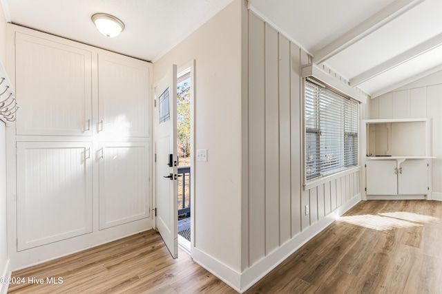 hall with light hardwood / wood-style floors, lofted ceiling, and wood walls