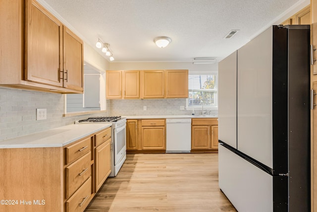 kitchen featuring sink, light brown cabinets, white appliances, decorative backsplash, and light wood-type flooring