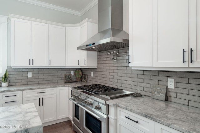 kitchen featuring ornamental molding, extractor fan, range with two ovens, and white cabinets