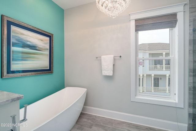 bathroom with an inviting chandelier, a tub to relax in, and hardwood / wood-style floors