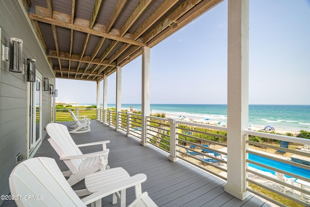 wooden terrace featuring a water view and a view of the beach