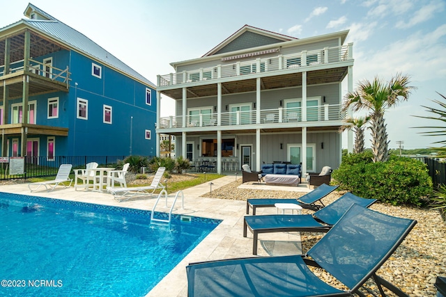 back of property featuring a fenced in pool, an outdoor bar, an outdoor living space, a patio area, and a balcony