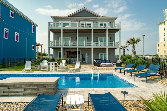 rear view of property with a fenced in pool, an outdoor living space, a patio area, and a balcony