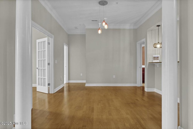 unfurnished room with crown molding, baseboards, and wood finished floors