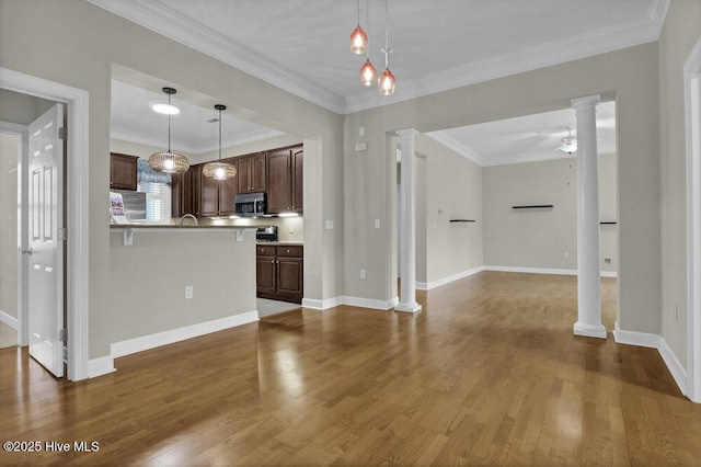 kitchen featuring decorative columns, stainless steel microwave, a ceiling fan, open floor plan, and wood finished floors