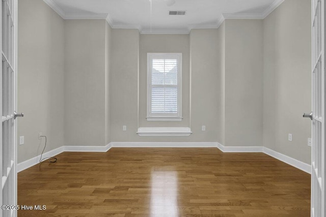 unfurnished room with baseboards, visible vents, wood finished floors, and ornamental molding