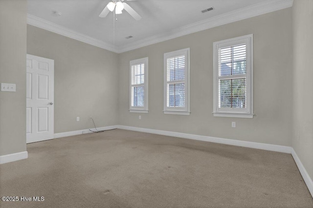 carpeted spare room featuring a ceiling fan, baseboards, visible vents, and crown molding