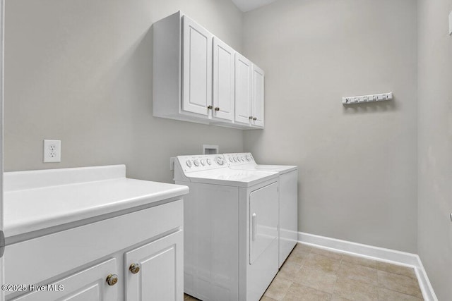 laundry area featuring washing machine and dryer, cabinet space, and baseboards