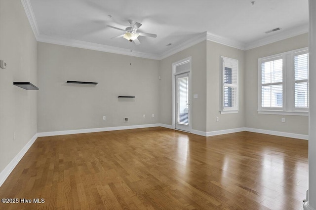 spare room with ornamental molding, wood finished floors, visible vents, and baseboards