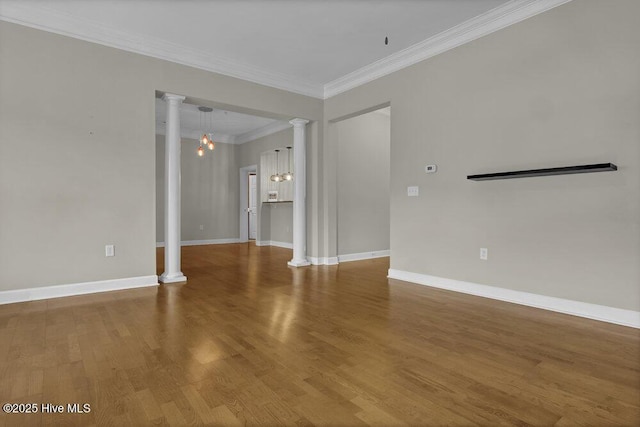 empty room with ornate columns, crown molding, baseboards, and wood finished floors