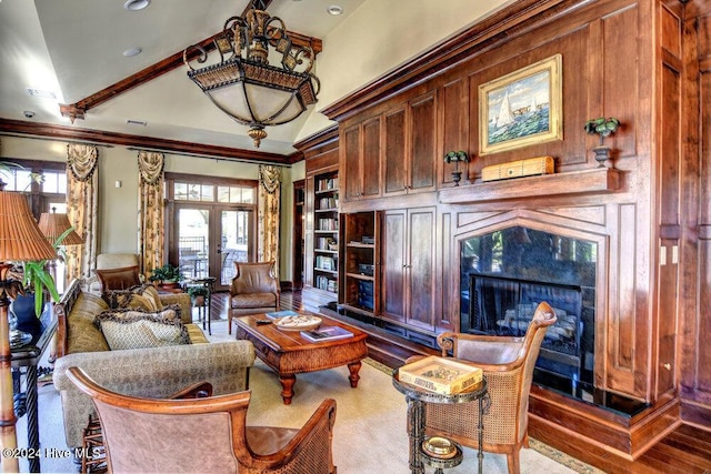 living room featuring a premium fireplace, wood finished floors, vaulted ceiling, french doors, and built in shelves