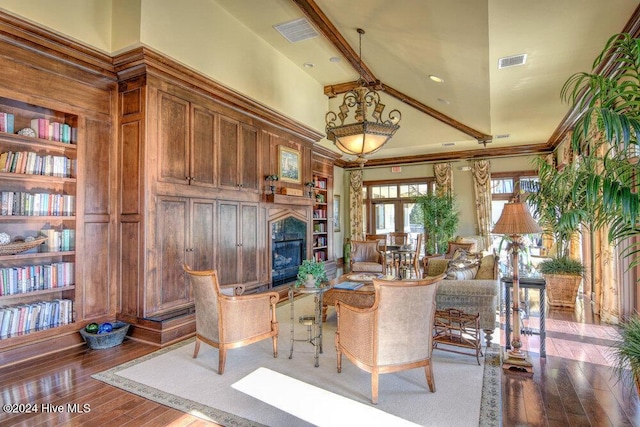 living area with wood-type flooring, a glass covered fireplace, visible vents, and built in features