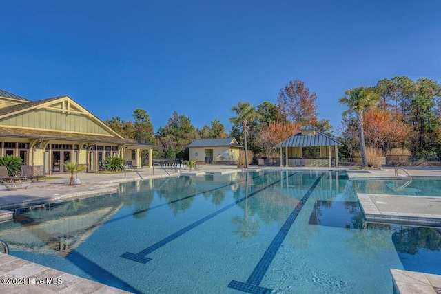 community pool with a patio area, fence, and a gazebo