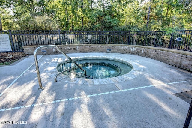 view of swimming pool with fence and a hot tub