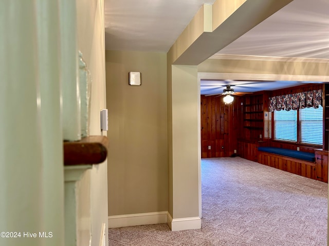 hall featuring wood walls, carpet, and ornamental molding