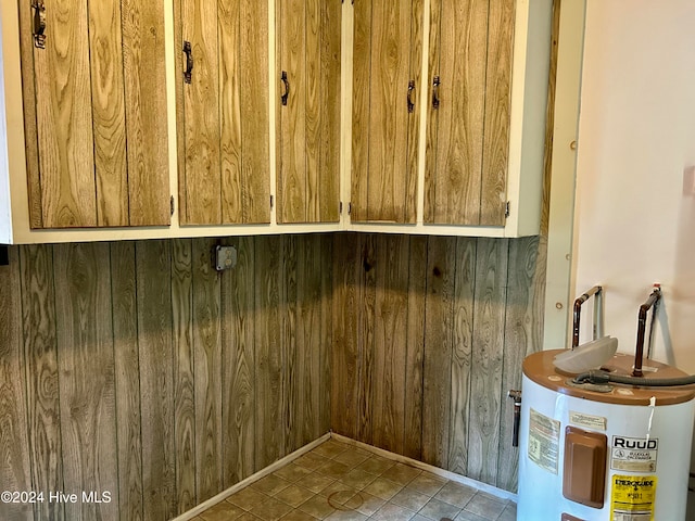 interior details with water heater, wooden walls, and tile patterned floors