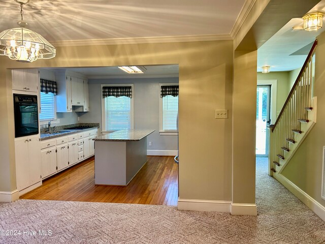 kitchen featuring a center island, white cabinets, light hardwood / wood-style flooring, sink, and black oven