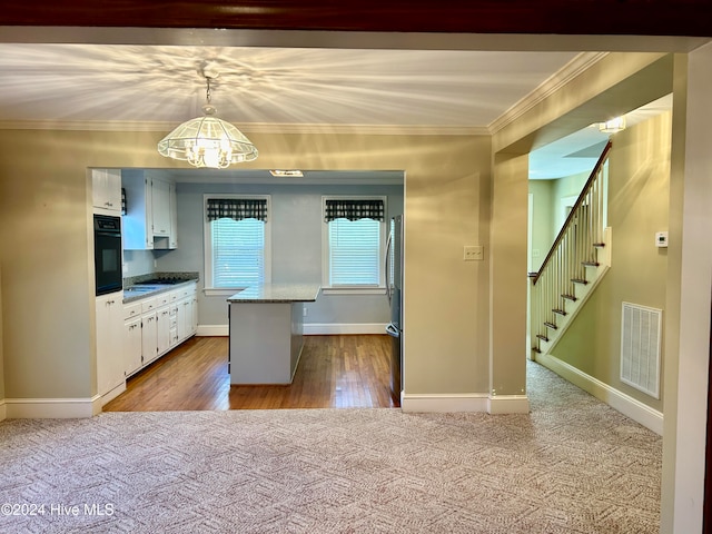 kitchen with oven, crown molding, white cabinetry, light wood-type flooring, and decorative light fixtures