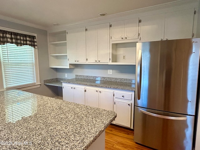 kitchen featuring white cabinetry, light stone countertops, light hardwood / wood-style flooring, and stainless steel fridge