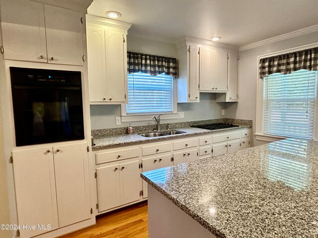 kitchen with white cabinets, plenty of natural light, black appliances, and ornamental molding