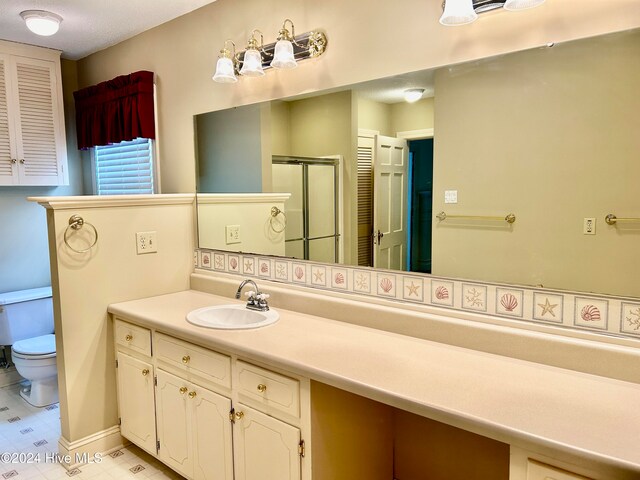 bathroom with a shower with door, vanity, and toilet