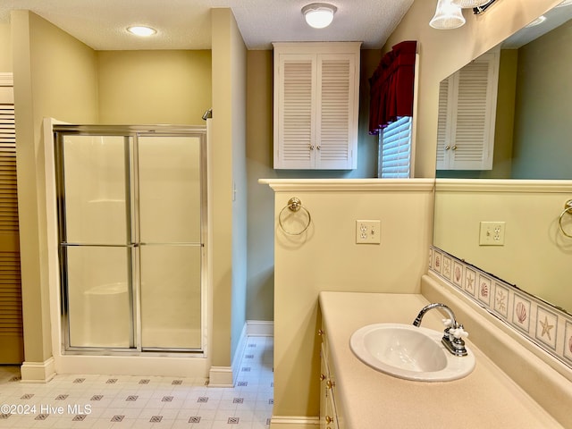 bathroom with vanity, a textured ceiling, and a shower with shower door