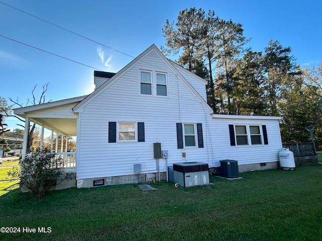 rear view of house with central AC unit and a yard