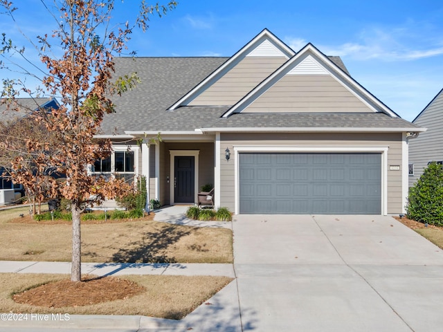 view of front facade with a garage, driveway, and a shingled roof