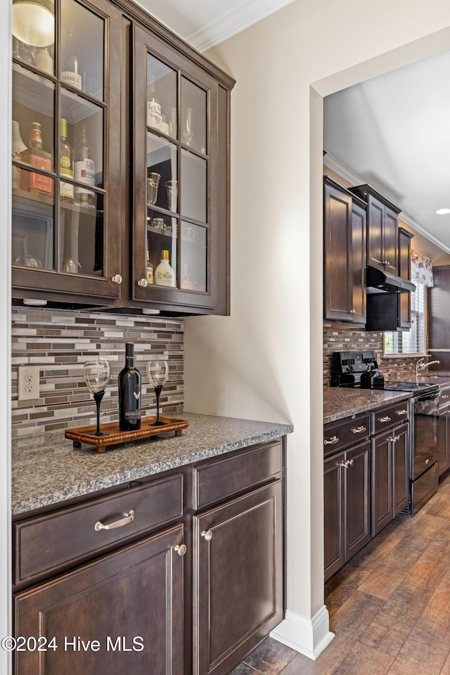 bar featuring black electric range oven, crown molding, under cabinet range hood, and decorative backsplash