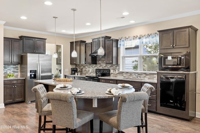 kitchen featuring dark brown cabinetry, appliances with stainless steel finishes, a kitchen breakfast bar, light wood-style floors, and a sink