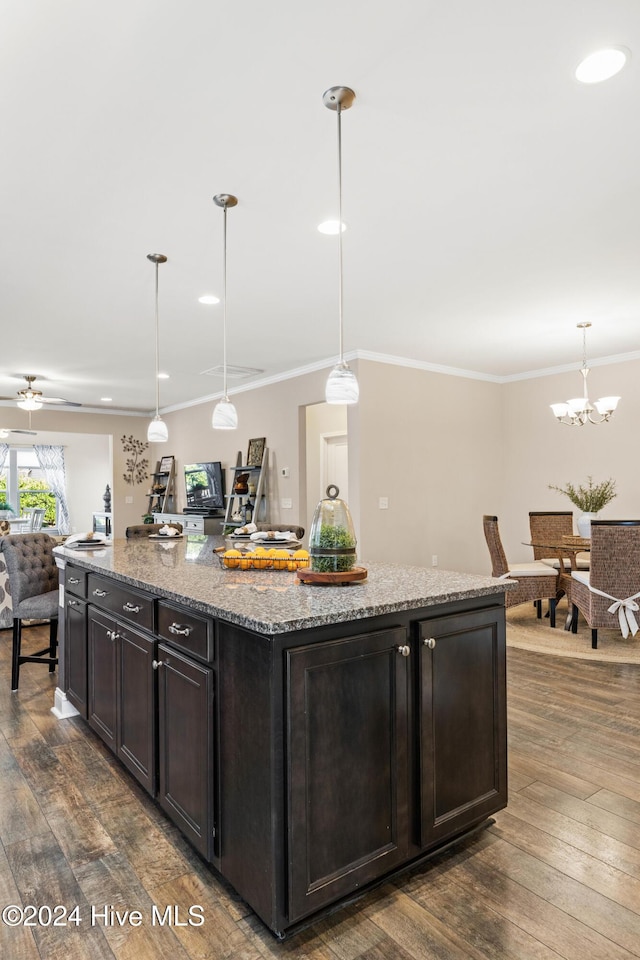 kitchen with dark wood-style floors, a kitchen island, ornamental molding, and open floor plan