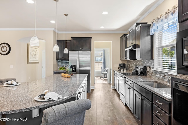 kitchen featuring appliances with stainless steel finishes, a breakfast bar, a sink, and ornamental molding