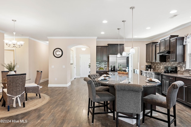 kitchen with under cabinet range hood, dark wood-style flooring, range with electric stovetop, stainless steel refrigerator with ice dispenser, and a center island with sink