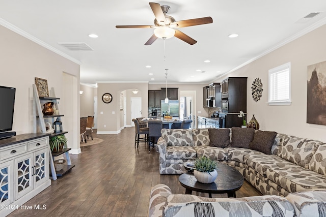 living room featuring arched walkways, crown molding, dark wood finished floors, visible vents, and baseboards