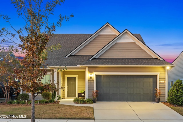 craftsman-style house featuring a garage, driveway, and roof with shingles