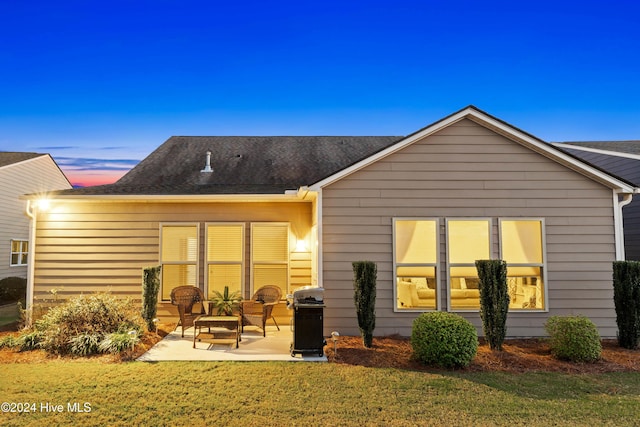 back of property at dusk featuring a lawn and a patio area