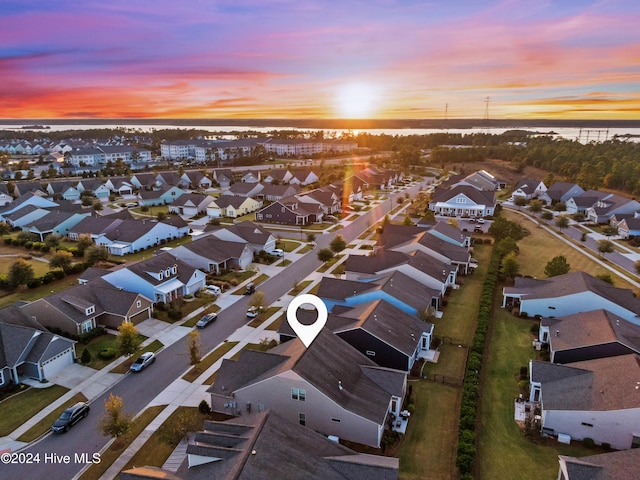 aerial view at dusk with a residential view and a water view