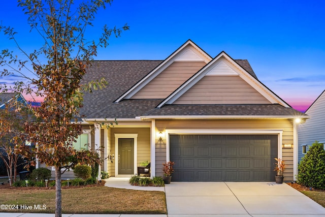 craftsman-style house with driveway, a shingled roof, and an attached garage