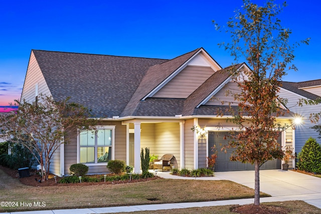 view of front of home with a garage, a shingled roof, and driveway